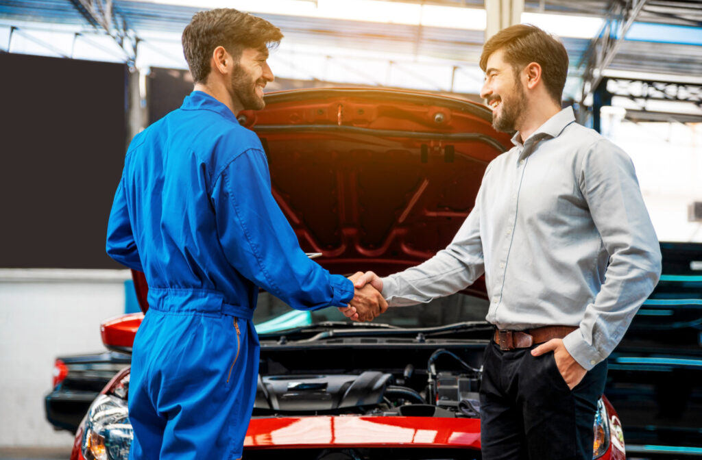 A car mechanic shaking hands with a male customer