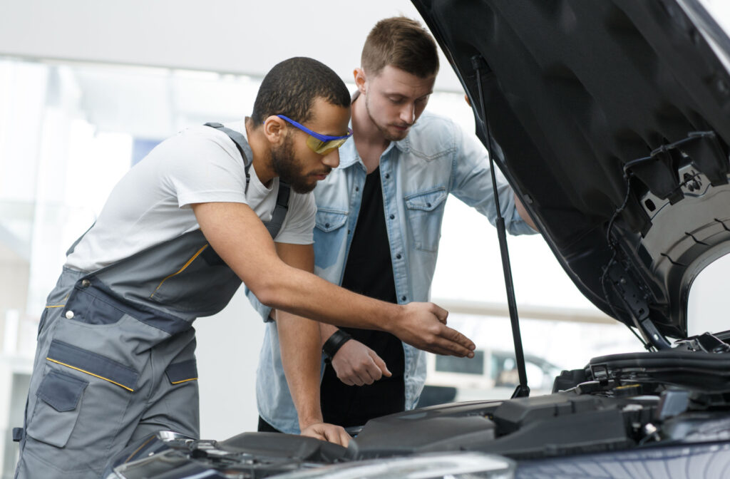 A radiator technician explains the cause of a car's radiator leak to the car owner