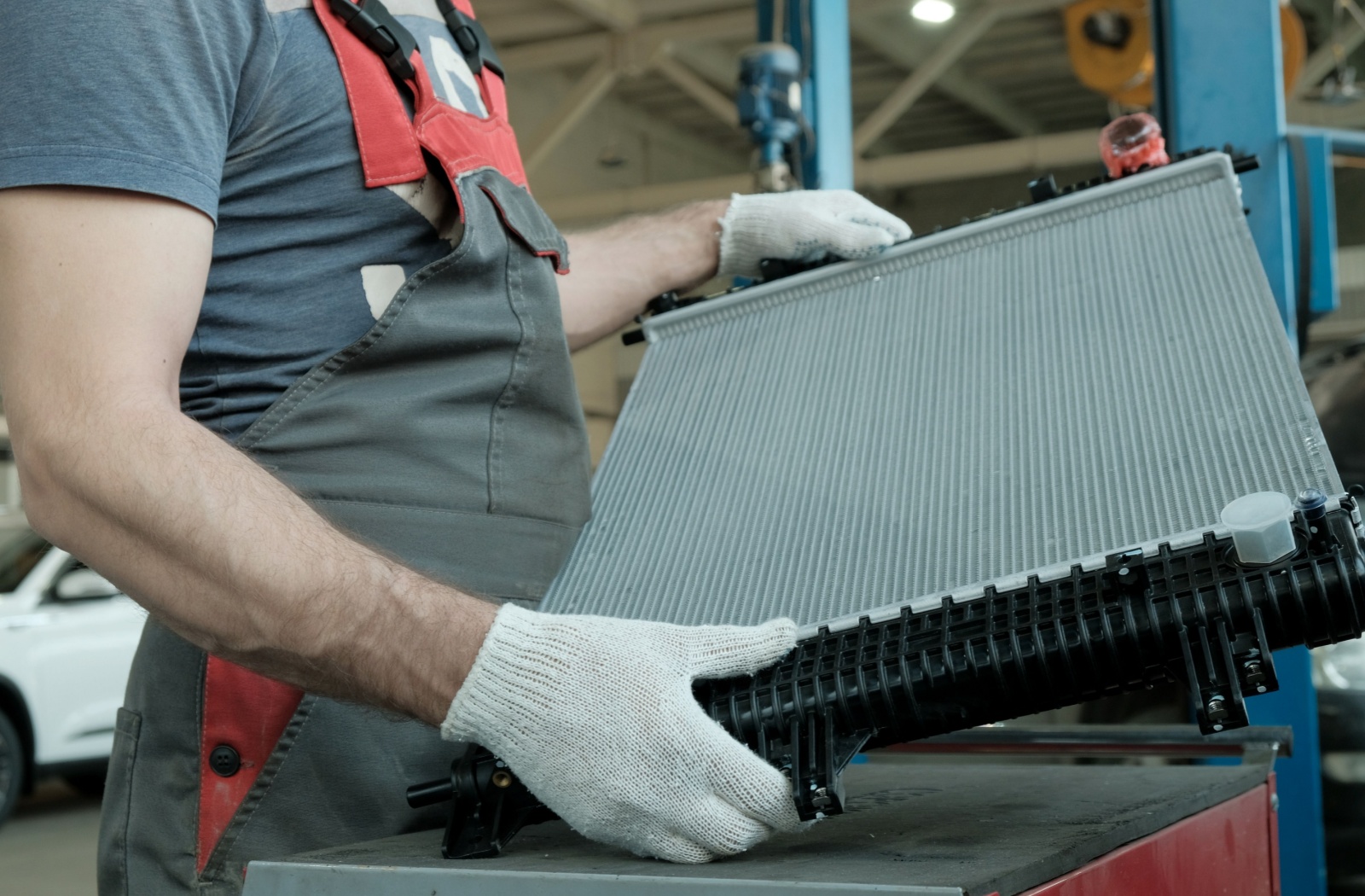 An automotive technician inspects an aluminum radiator before installing it in a vehicle.