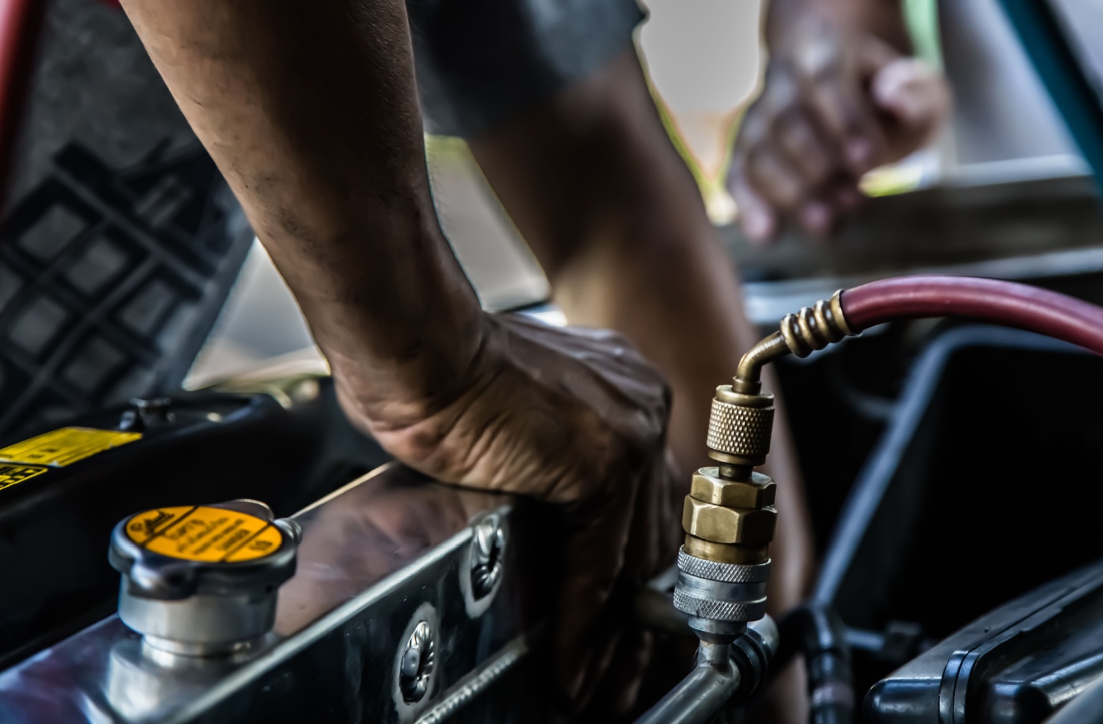 A close-up image of an automotive technician pressure testing a truck's cooling system repair.