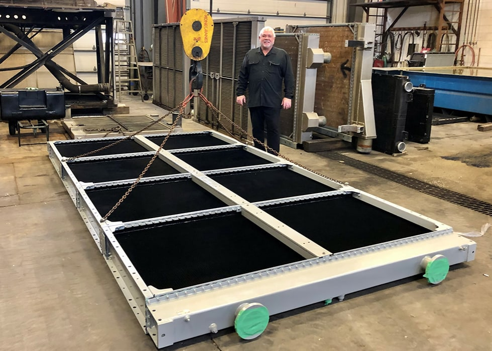 A man stands beside a large, rectangular platform with pulleys overhead