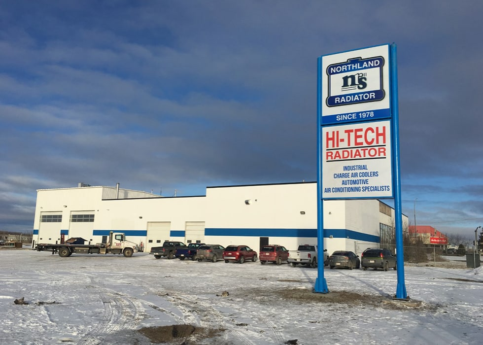 A large building with a sign displays radiator services amidst a snowy landscape