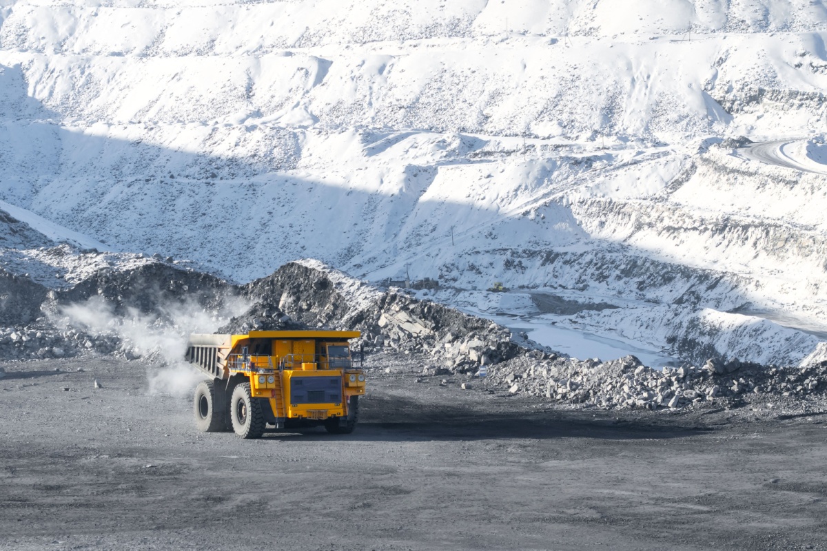 Large mining dump truck working in open pit mine during winter with exhaust visible in cold air, highlighting the importance of winterized cooling systems for heavy equipment.
