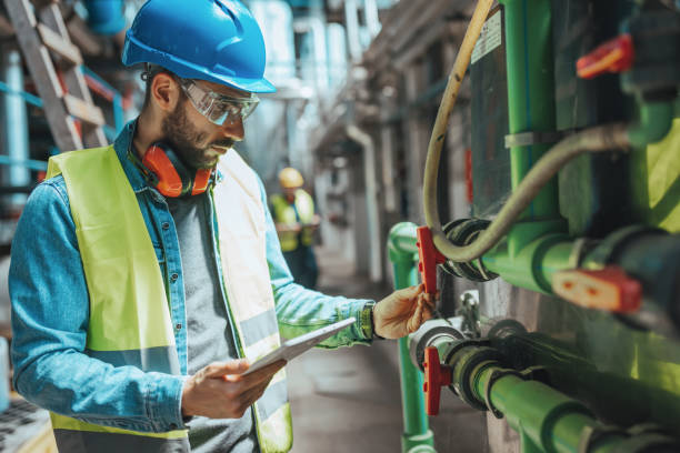 Worker inspecting machinery near industrial radiators in a construction area