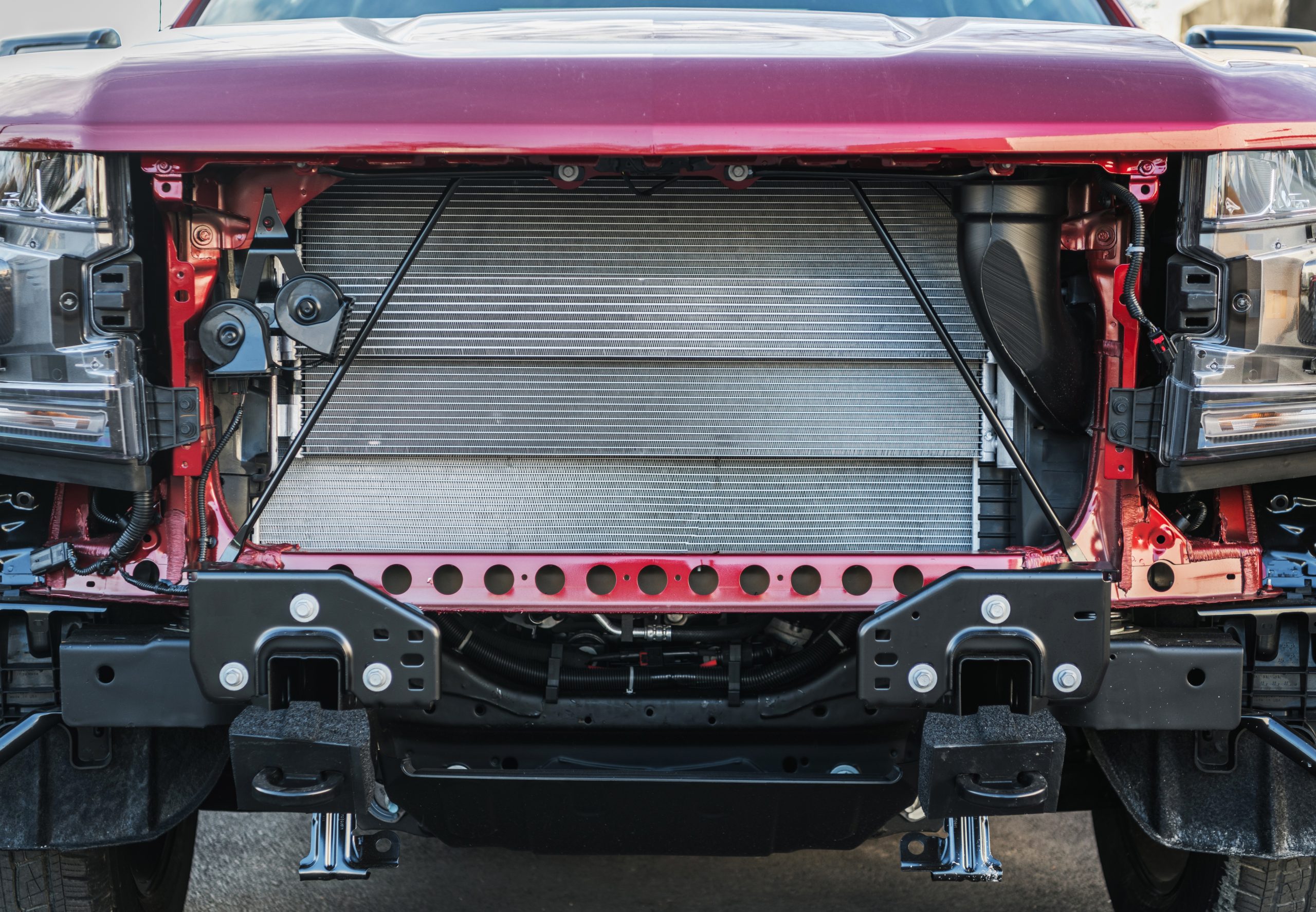 A red truck's front end displays exposed components and a large cooling radiator