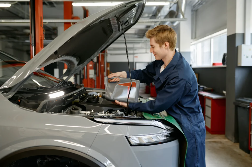 A young mechanic checks the oil level in a car engine