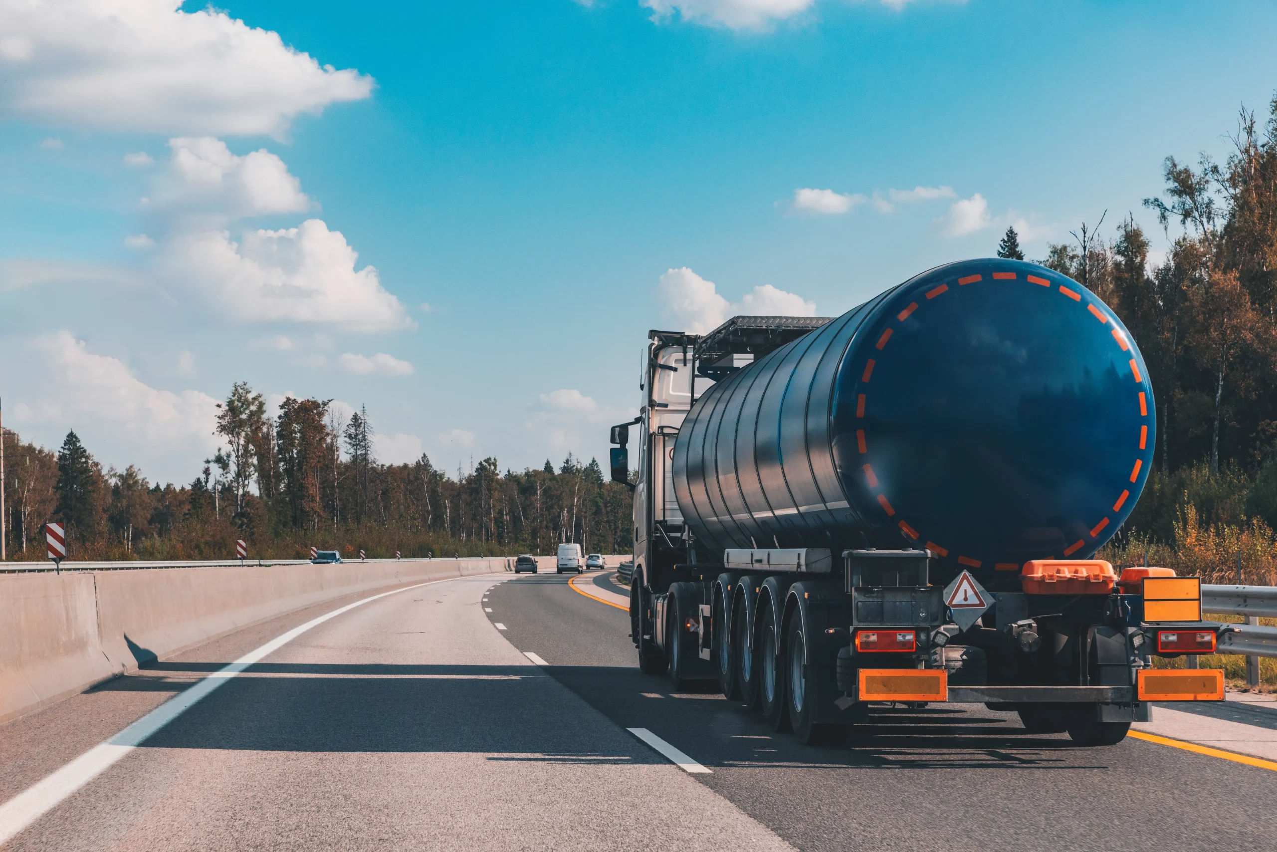 Blue tanker truck transporting fuel and gas tanks on a highway