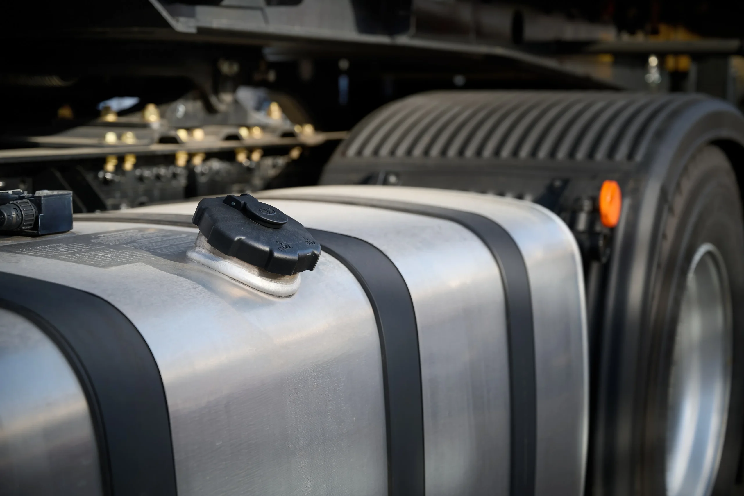 Metal fuel tank placed beside a large truck tire in an industrial setting