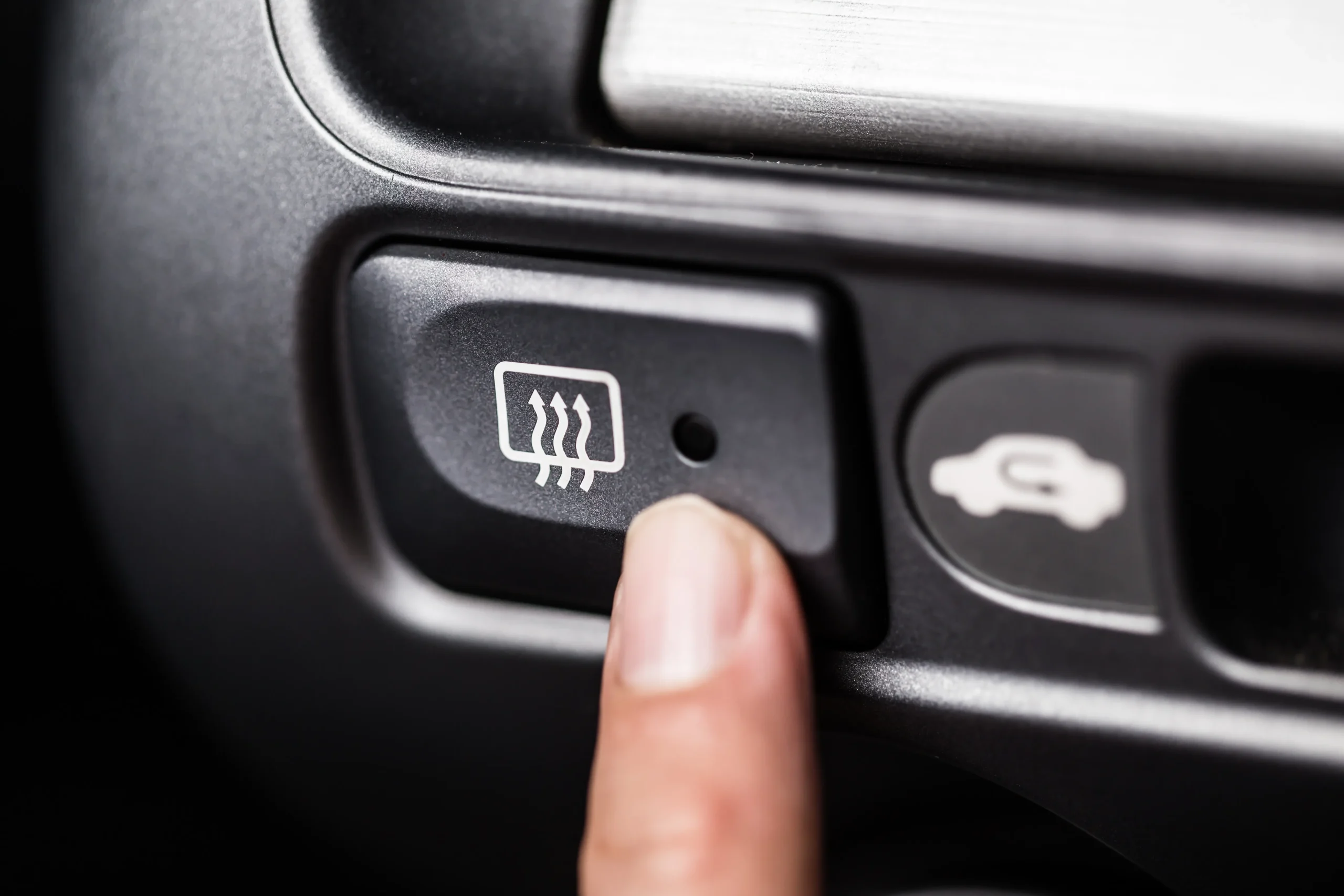 Heaters button pressed to activate heated car windows for defrosting