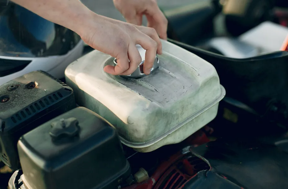A hand is removing a cap from a metal engine cover