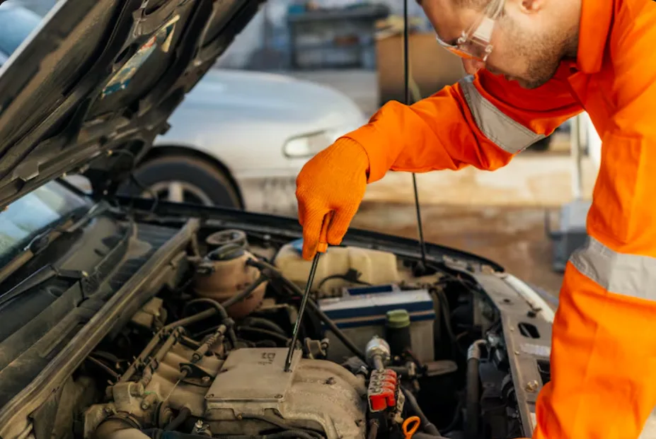 Mechanic inspects engine components near fuel gas tanks under a car's hood