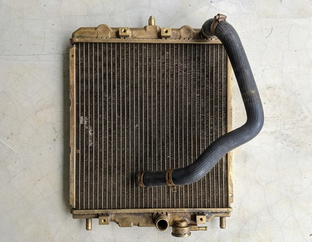 A metallic radiator displays a curved rubber hose connected to its side