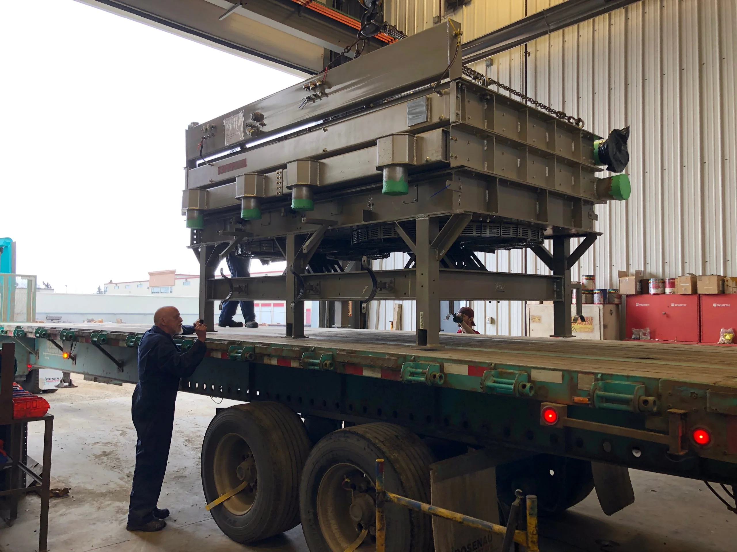 A worker secures machinery being unloaded from a truck in a warehouse