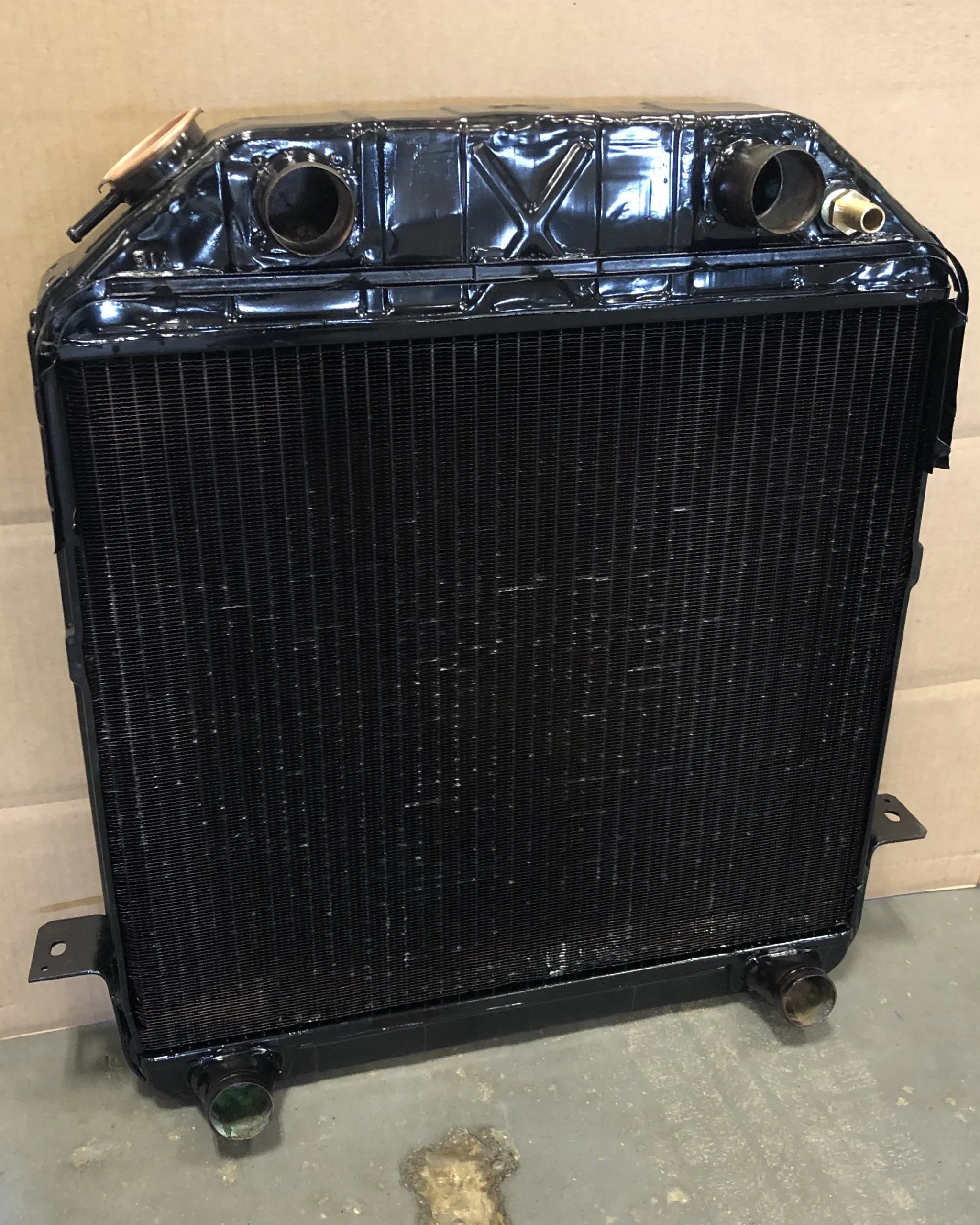 A black radiator with two openings sits on a flat surface