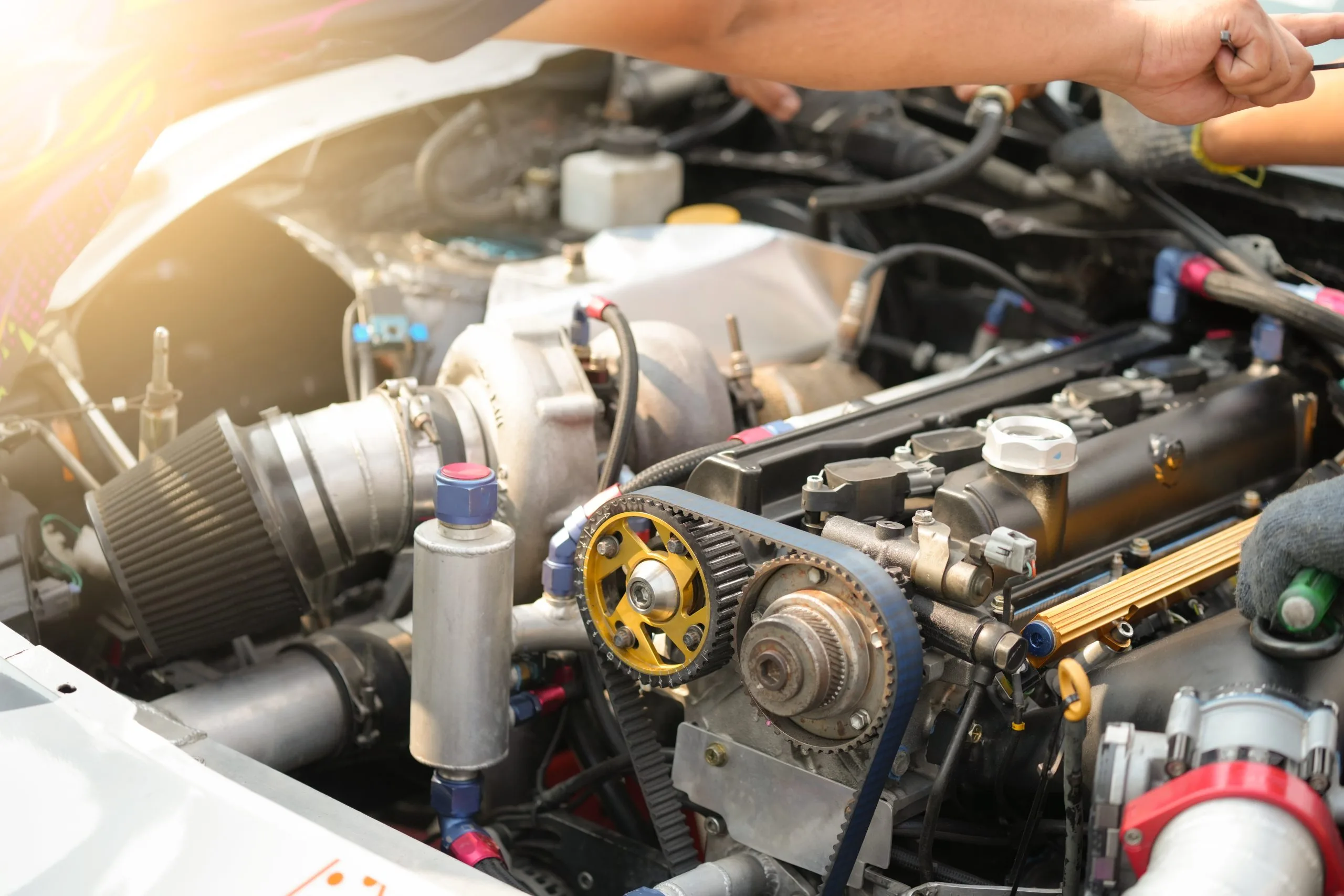 A technician works on a car's engine, adjusting components with tools